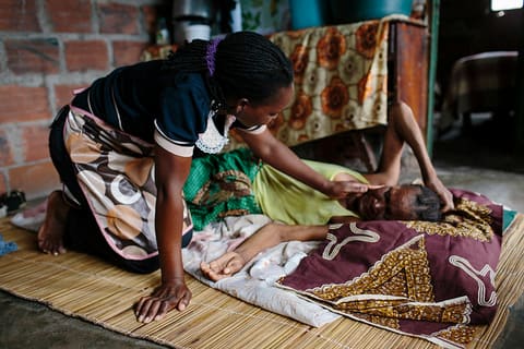 Celina comforts HIV-positive patient, Felizmina, in the Maxaquena township on the outskirts of Maputo
