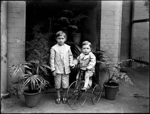 Two small boys, one on tricycle