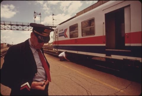 Conductor checks his watch to find out how much time remains at the Bloomington, Illinois, stop on the turboliner run between St. Louis, Missouri, and Chicago, June 1974