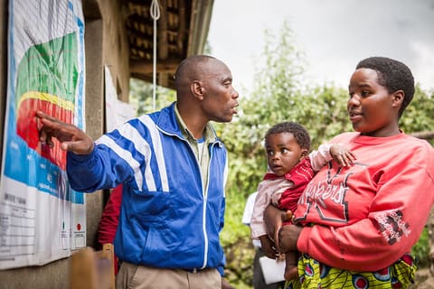 Educating and Empowering Mothers in Rwanda: A “Be the Change” volunteer explains to a mother how to use a growth monitoring chart.