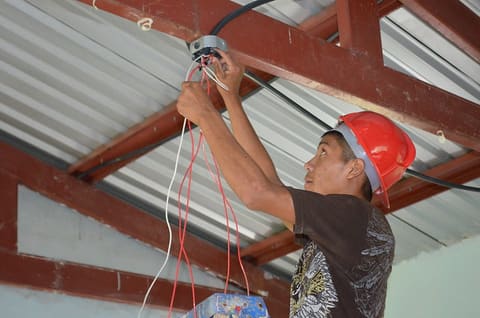 USAID ProParque trainee installs wiring for solar panel at public school